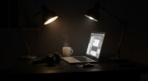 Dark themed night office with glowing laptop, ambient desk lamp, headphones, Pixlelo.com Variation 88